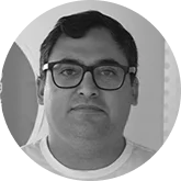 Head-and-shoulders portrait of a man with short dark hair and glasses, looking at the camera.